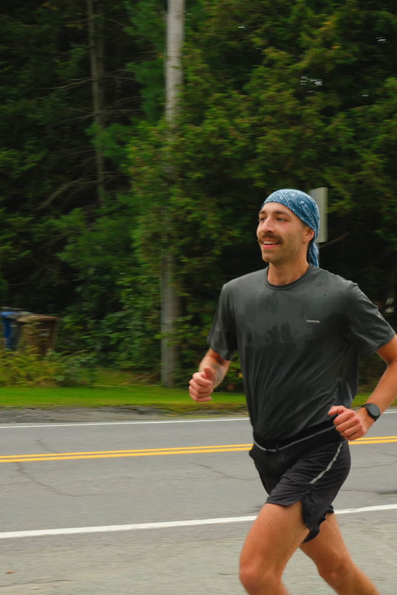 Un coureur souriant, bandana sur la tête, dans les derniers kilomètres.