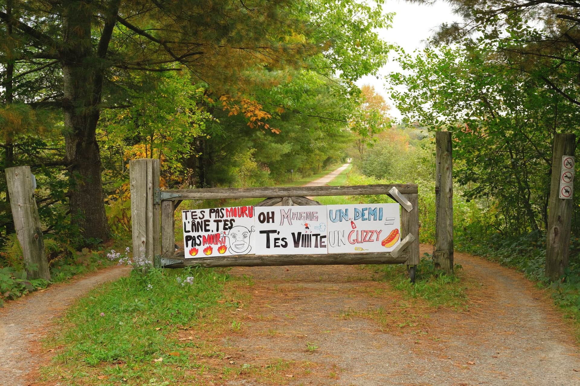 Une barrière de bois à l'entrée du sentier, couverte de pancartes d'encouragement faites à la main.